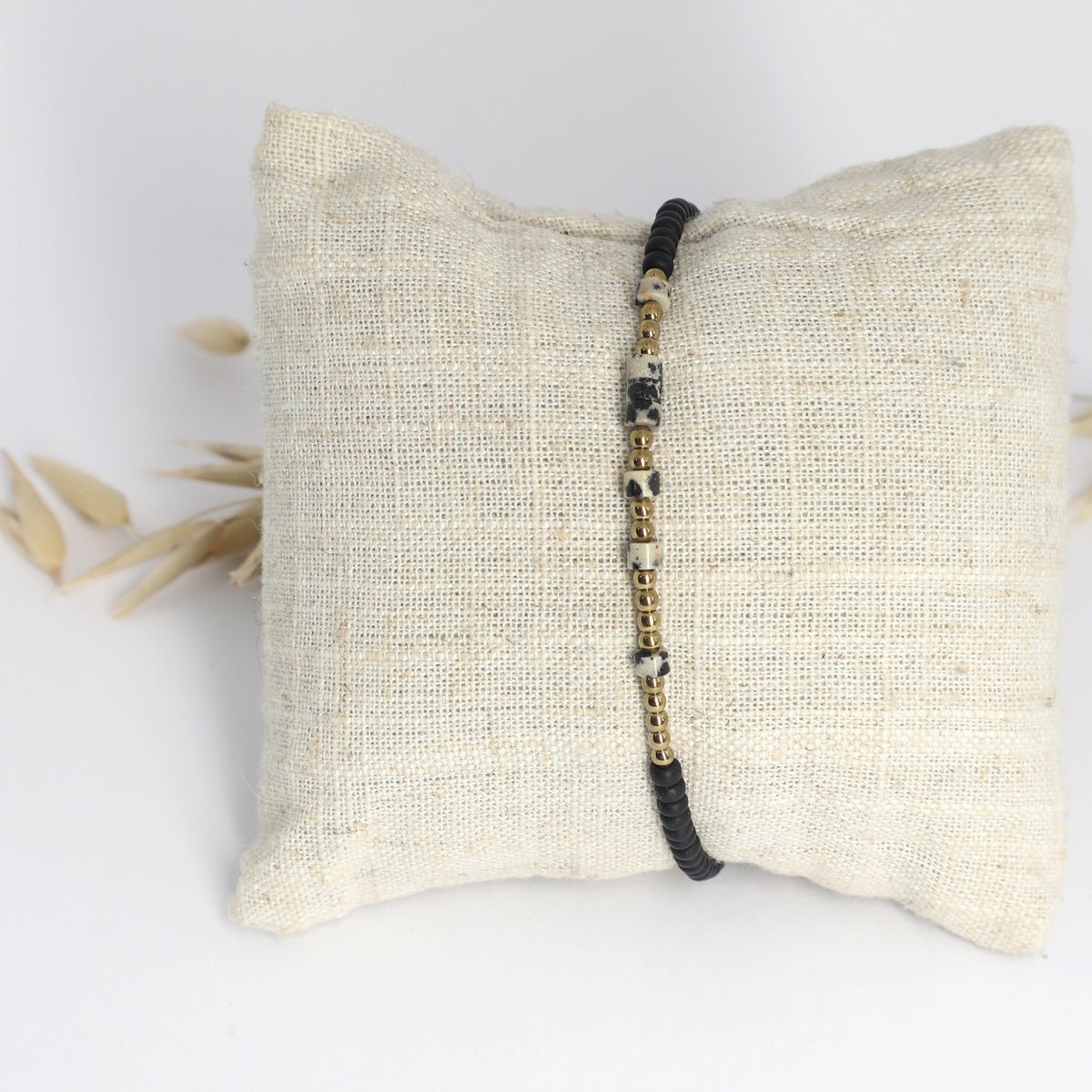 Morsecode Armband Selflove mit schwarzen und goldenen Perlen auf Stoffkissen präsentiert