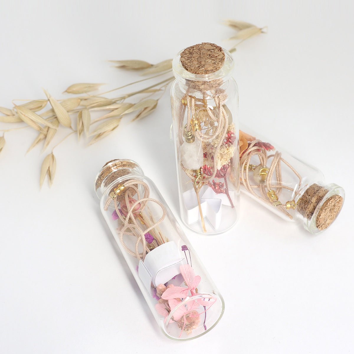 Drei Edelstein Armbänder in Glasflaschen mit Trockenblumen und Motivationsspruch
