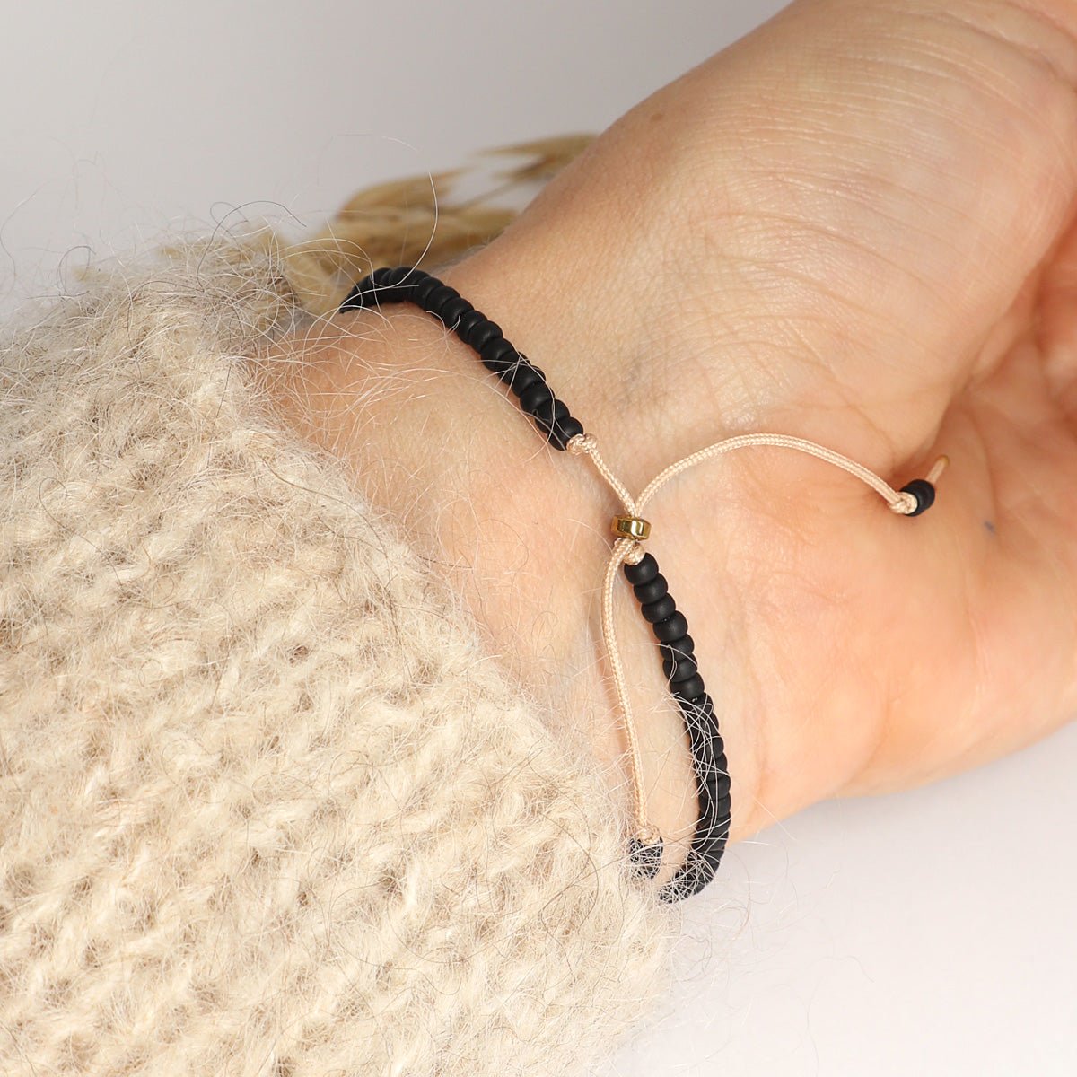 Morsecode Armband Selflove mit schwarzen und goldenen Perlen am Handgelenk getragen - Rückseite