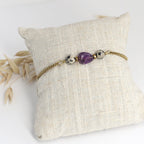 Vergoldetes Edelstahlarmband mit Amethyststeinen liegt auf Schmuckkissen