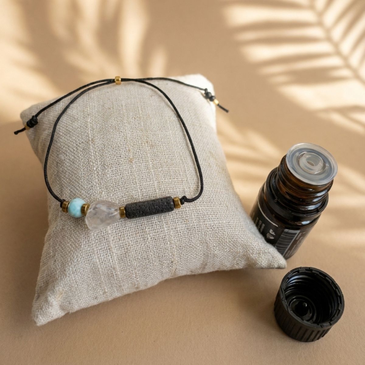 Größenverstellbares Aromatherapie Armband auf einem Kissen liegend neben einem braunen Fläschchen für ätherische Öle.