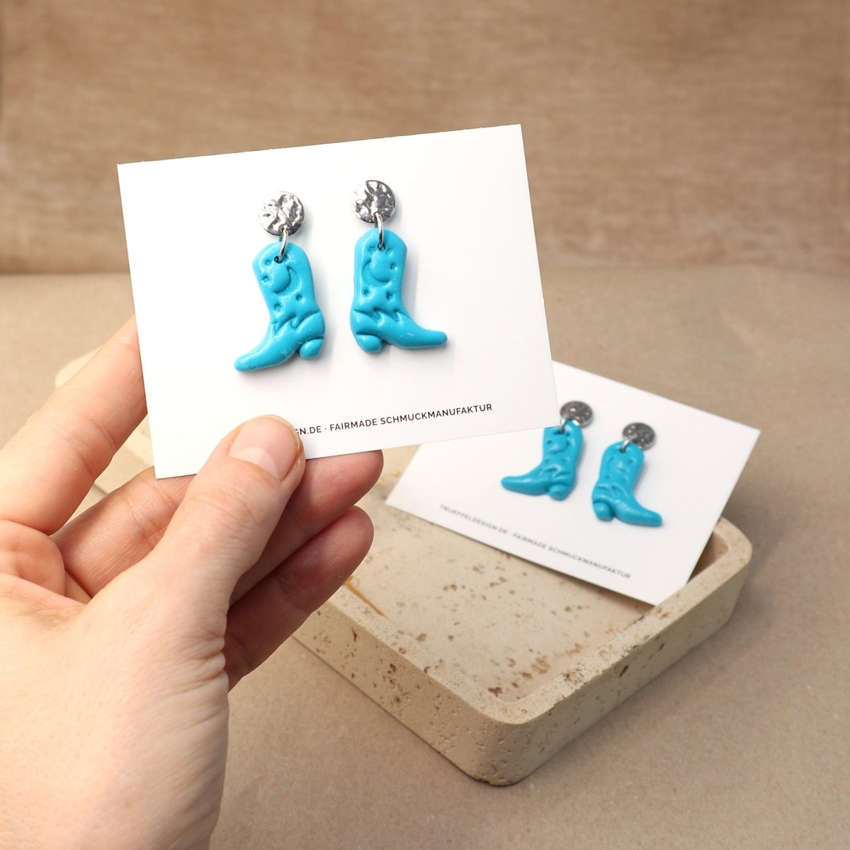 Hand hält Schmuckkarte mit Cowboy Boots Ohrringen aus Edelstahl