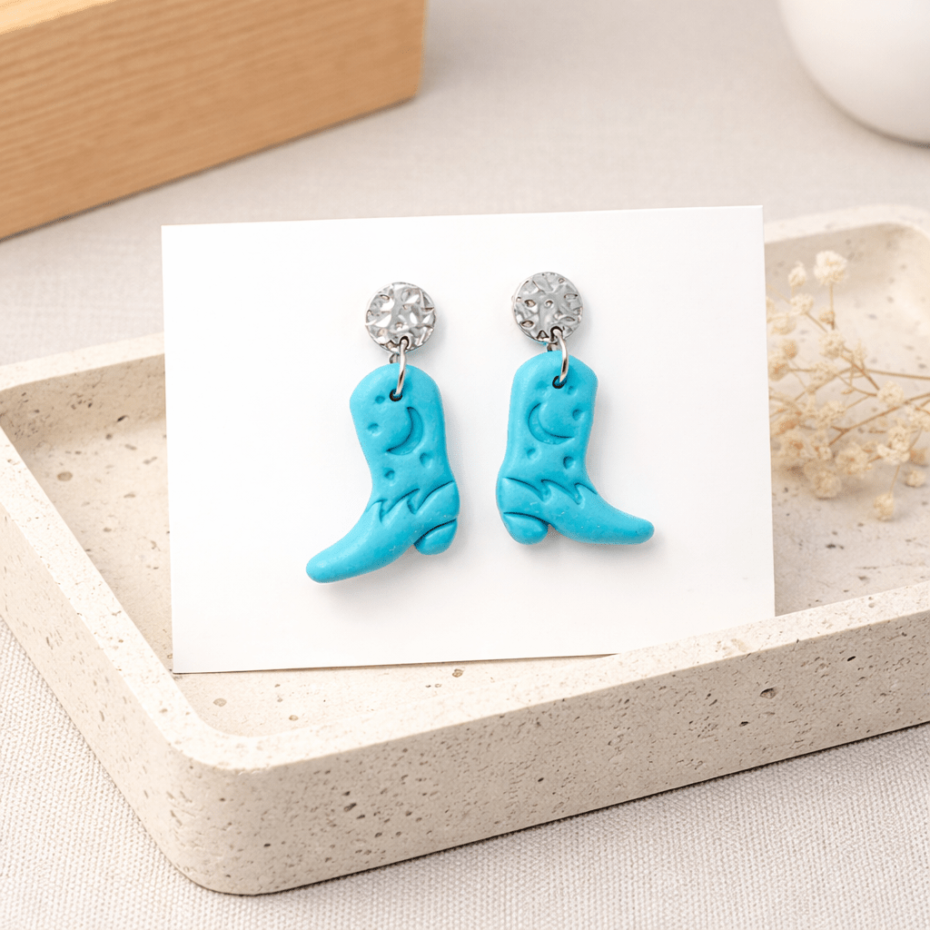 Türkise Cowboy-Boots-Ohrringe aus Edelstahl auf Schmuckkarte in Schmuckschale