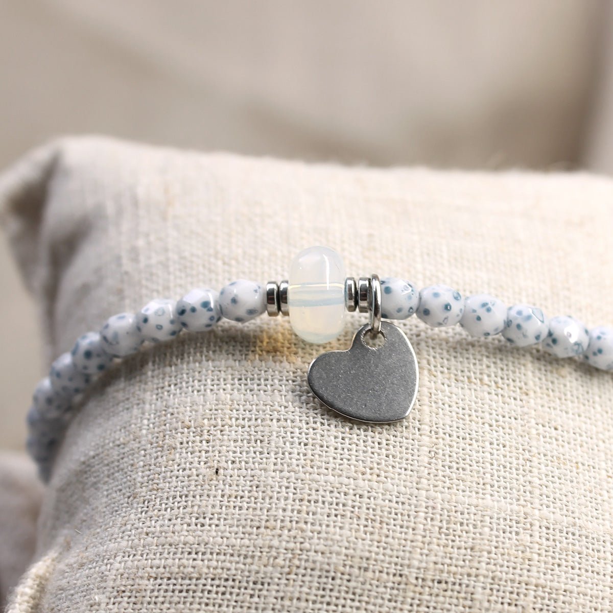 Nahaufnahme des 10 mm silbernen Herz-Anhängers aus Edelstahl an einem blauen 4 mm Perlenarmband