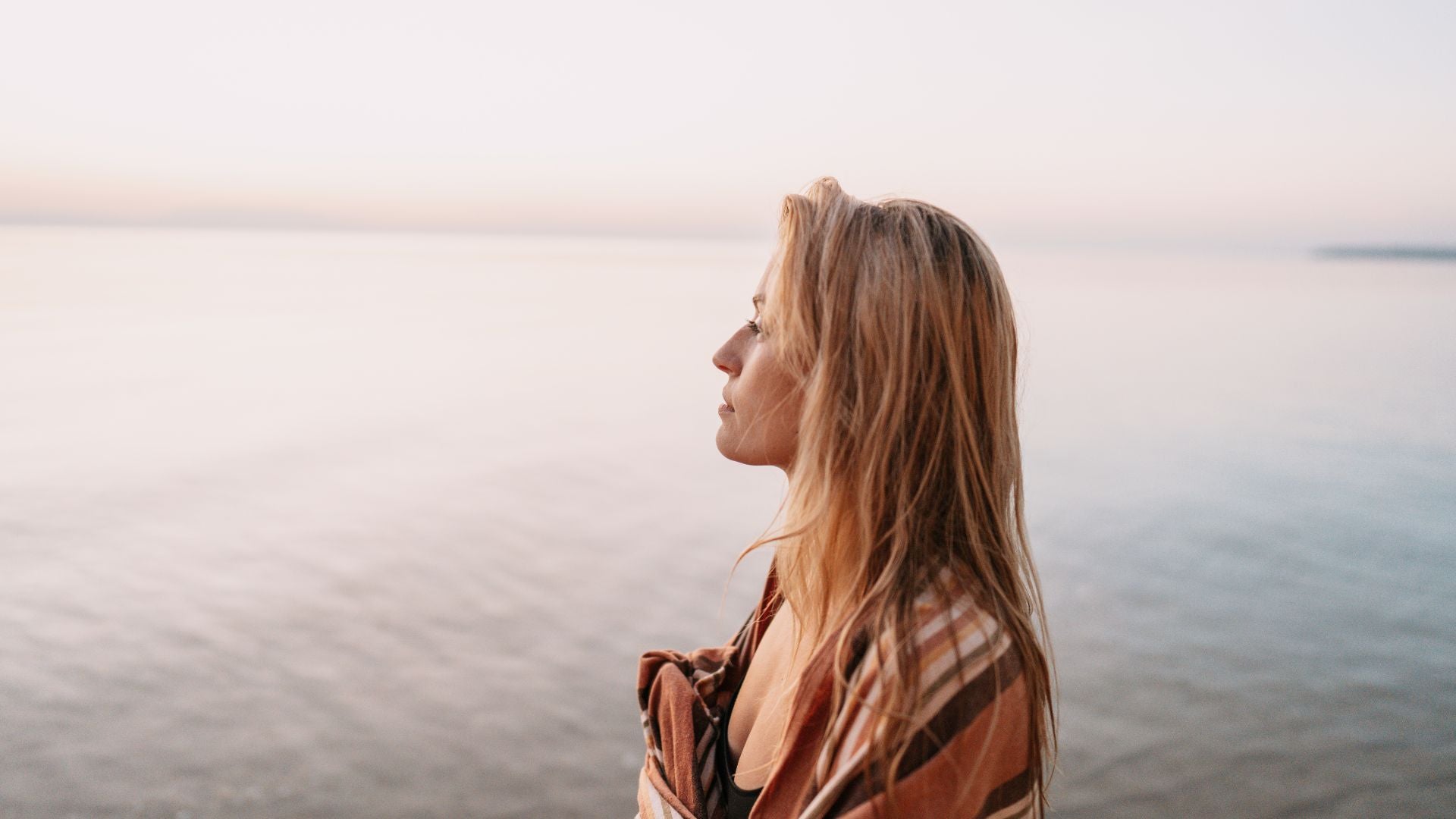 Frau steht in der Natur und genießt den weiten Ausblick