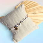 Karma Armband mit Mondstein-Kugeln stilvoll dekoriert auf einem kleinen Stoffkissen. trueffeldesign