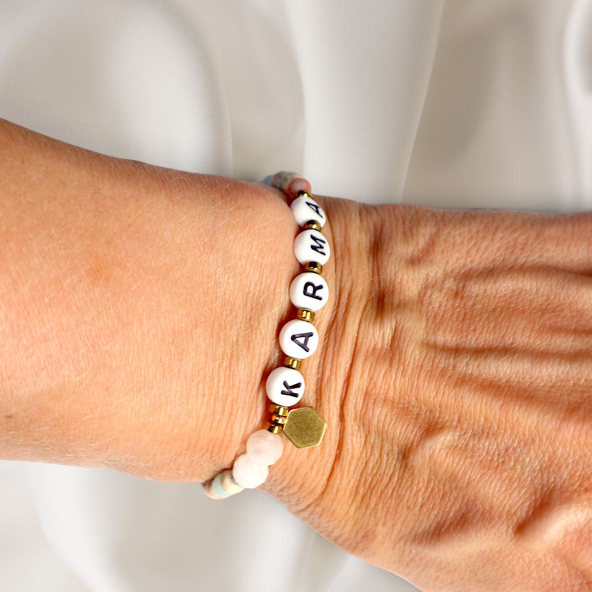 Karma Armband mit Mondstein-Perlen und Buchstaben-Perlen getragen am Handgelenk. trueffeldesign