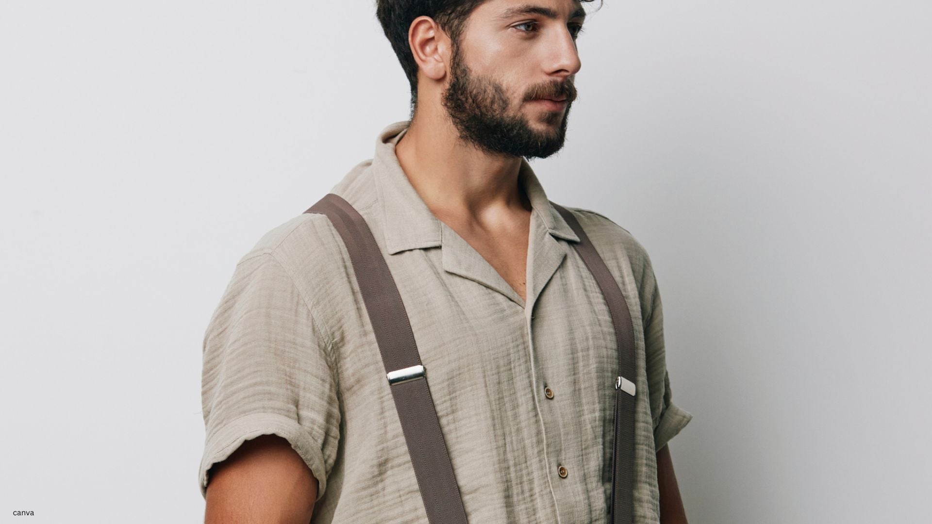 Mann mit Bart trägt Hosenträger und präsentiert stilvoll Männerschmuck