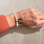 Buntes Perlenarmband Gold mit goldenem Mantra-Anhänger am Handgelenk getragen – wasserfester Schmuck