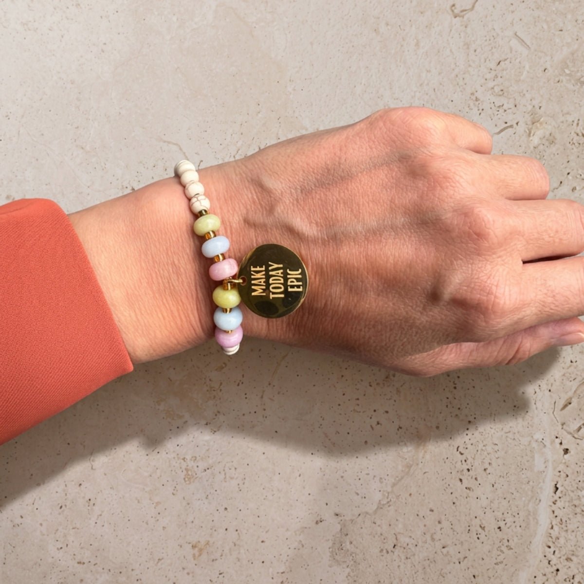 Buntes Perlenarmband Gold mit goldenem Mantra-Anhänger am Handgelenk getragen – wasserfester Schmuck