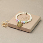 Mantra Armband Gold mit bunten Perlen auf cremefarbener Geschenkbox – Geschenkidee positive Energie