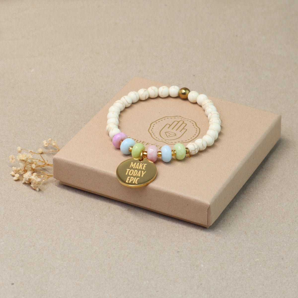 Mantra Armband Gold mit bunten Perlen auf cremefarbener Geschenkbox – Geschenkidee positive Energie