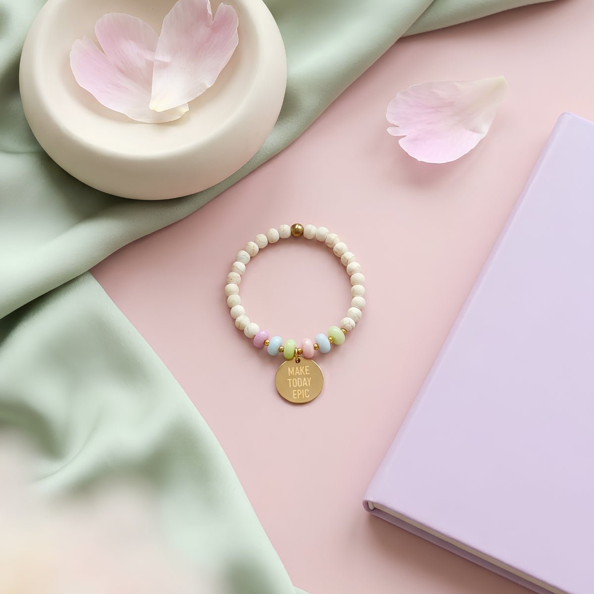 Mantra Armband Gold auf pastellfarbenem Hintergrund mit Rosenblüten – Geschenkidee positive Energie