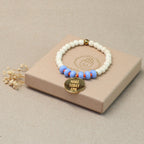Mantra Schmuck Damen – blaues Perlenarmband mit goldenem Plättchen auf beiger Geschenkbox