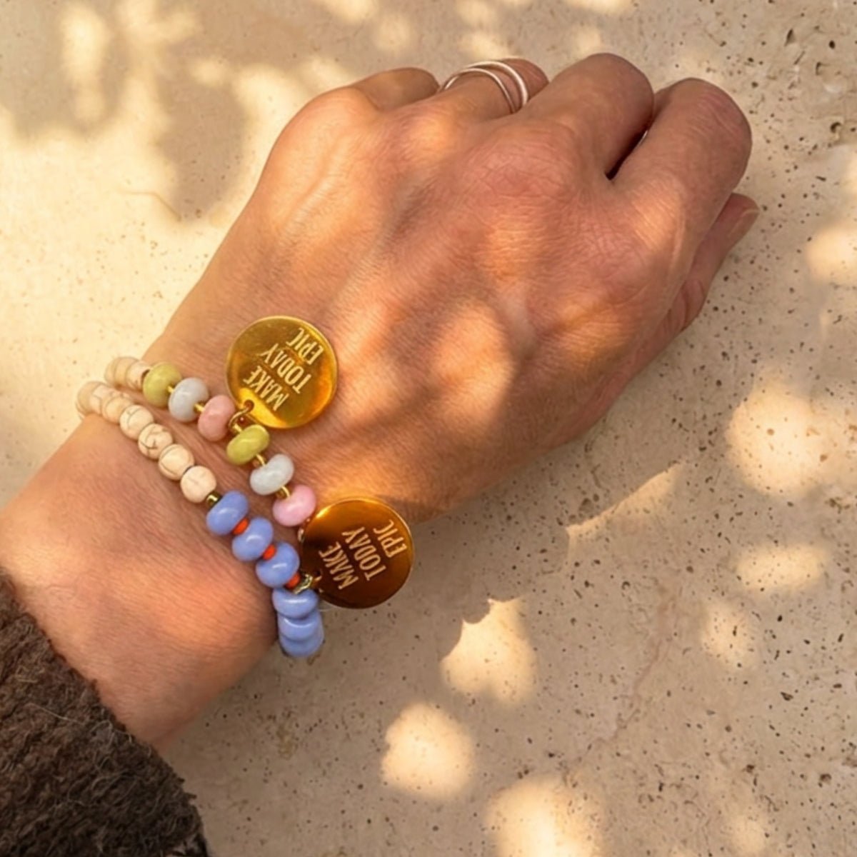 Mantra Schmuck Damen – blaues Perlenarmband und rosé Perlenarmband mit Gold-Plättchen im Sonnenlicht gestapelt
