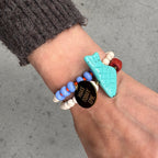 Mantra Schmuck Damen – blaues Perlenarmband mit goldenem Plättchen und türkisfarbenem Anhänger am Handgelenk