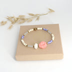 Boho-Armband mit rosa Fischanhänger liegt auf brauner Schmuckbox