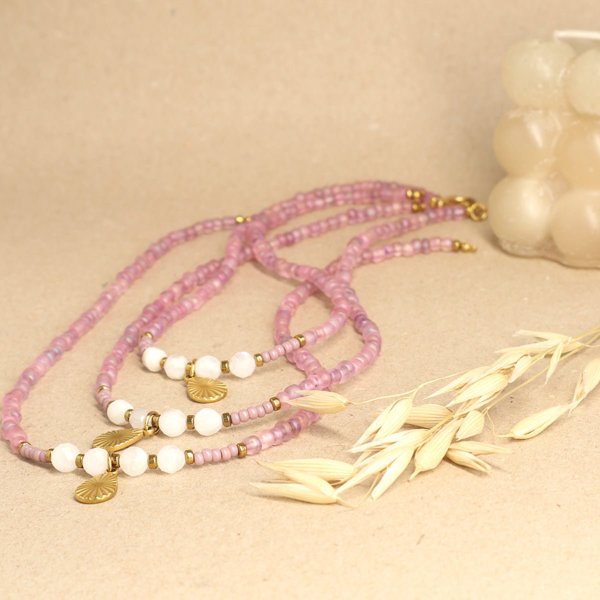 Mehrere schlichte Mondstein-Ketten liegen neben Trockenblumen