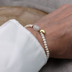 Tragebild des filigranen Mondstein-Perlenarmbands am Handgelenk einer Frau im Hochformat.