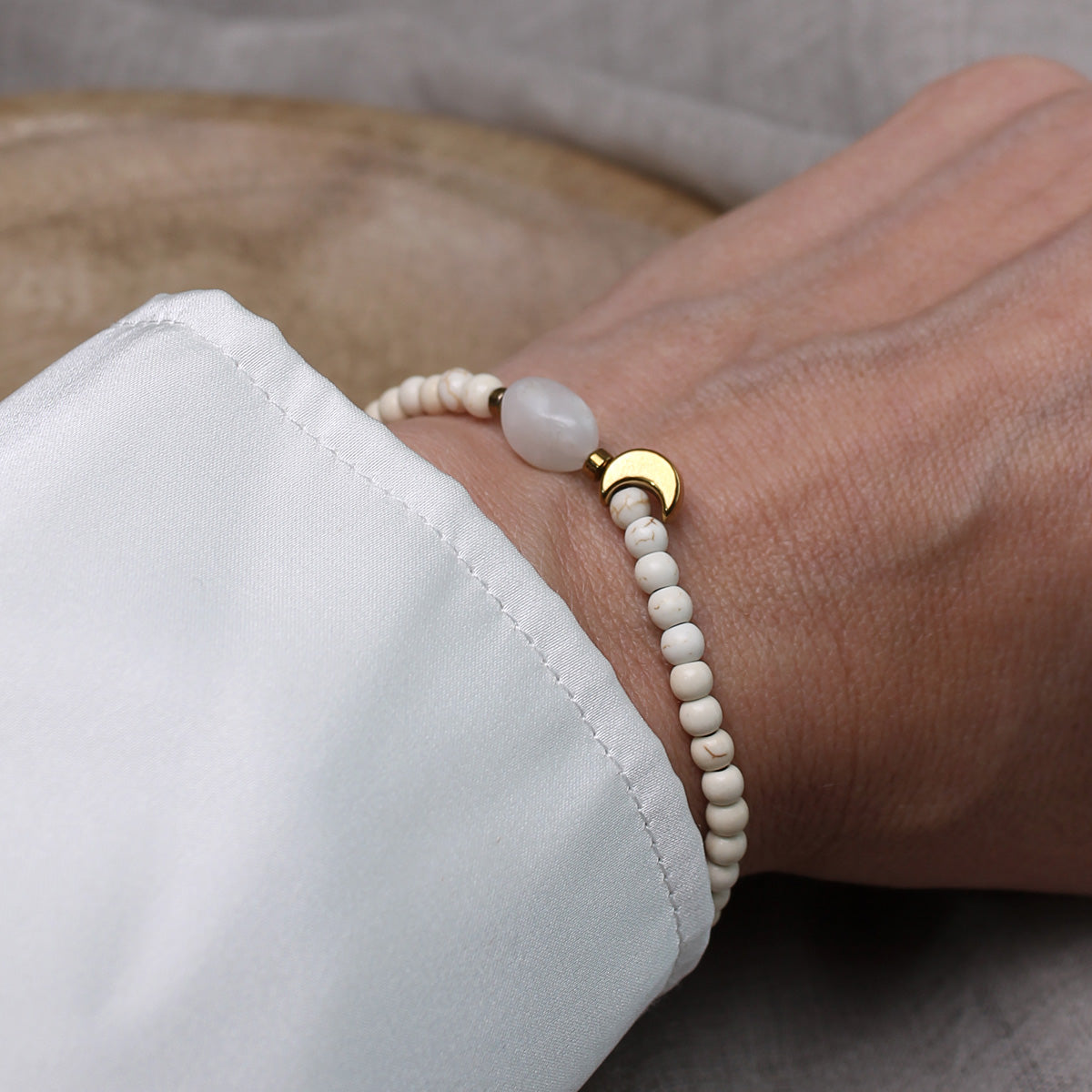 Tragebild des filigranen Mondstein-Perlenarmbands am Handgelenk einer Frau im Hochformat.