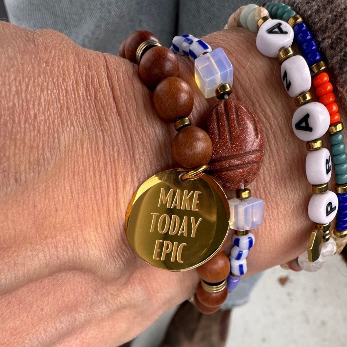 Perlenarmband aus Natursteinen und Holz kombiniert mit anderen bunten Perlenarmbändern als Layering-Look.