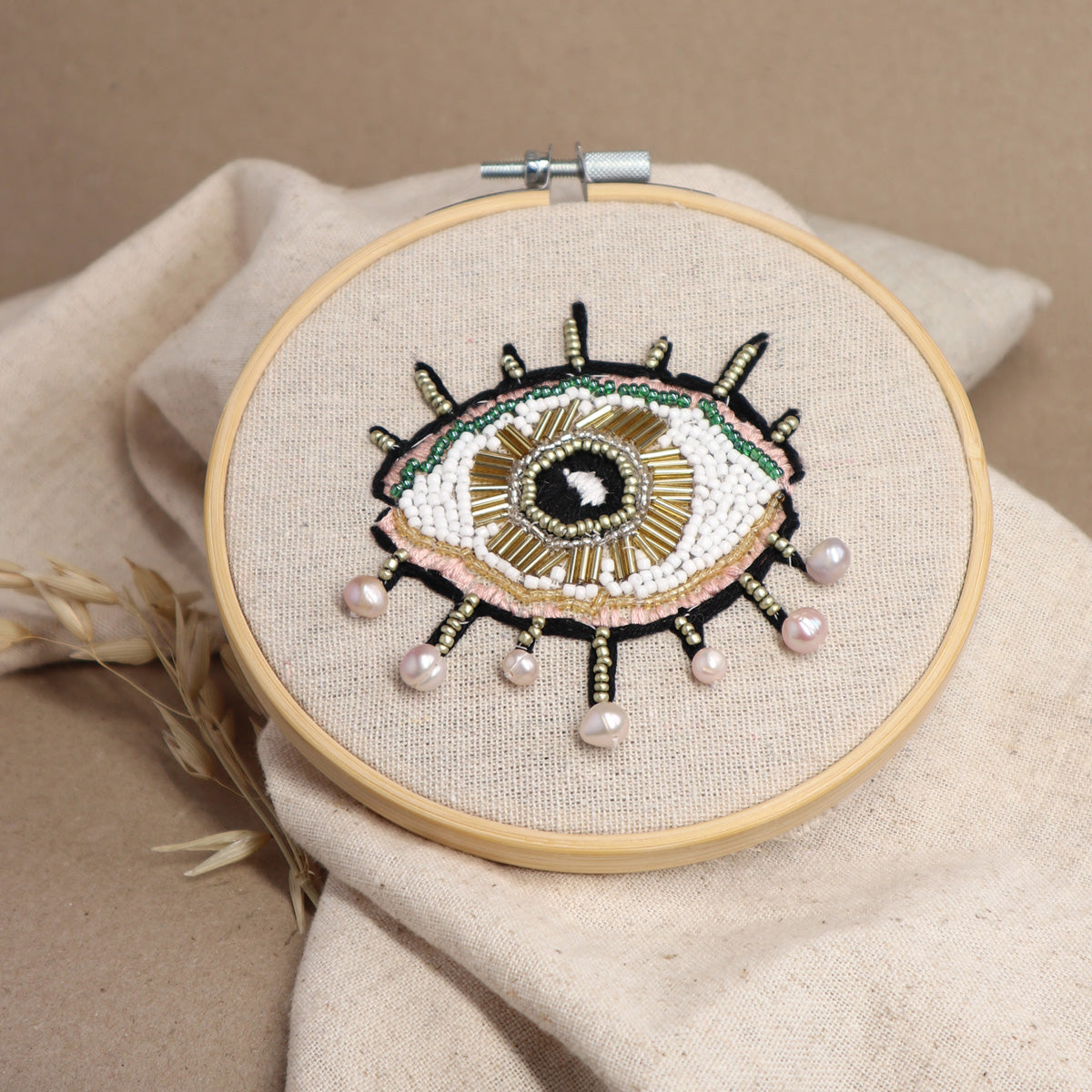 Ein mit Perlen besticktes Auge in einem hölzernen Stickrahmen als Kurs-Beispiel für den Perlensticken Workshop in Köln.