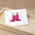 Pinke Cowboy-Boots-Ohrringe liegen auf Schmuckkarte in heller Schmuckschale