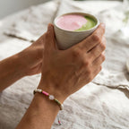 Tragebeispiel des Rosenquarz-Armbands Matcha Strawberry kombiniert mit einem Matcha Latte in einer ästhetischen Cafe-Atmosphäre | trueffeldesign