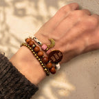 Detailaufnahme eines Sandelholz-Armbands mit Gravur-Plättchen am Handgelenk im warmen Sonnenlicht.