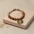 Sandelholz-Perlenarmband für Herren & Damen auf hellem Podest – minimalistisches Produktfoto mit goldenem Anhänger