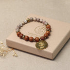 Sandelholz-Perlenarmband für Herren & Damen auf hellem Podest – minimalistisches Produktfoto mit goldenem Anhänger