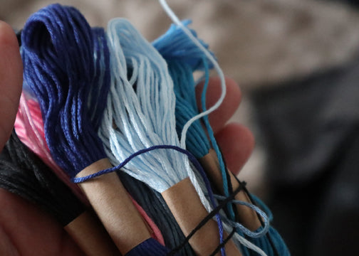 Verschiedene blaue und pinke Stränge Stickgarn für den kreativen Stickkurs in Köln bereitgelegt.