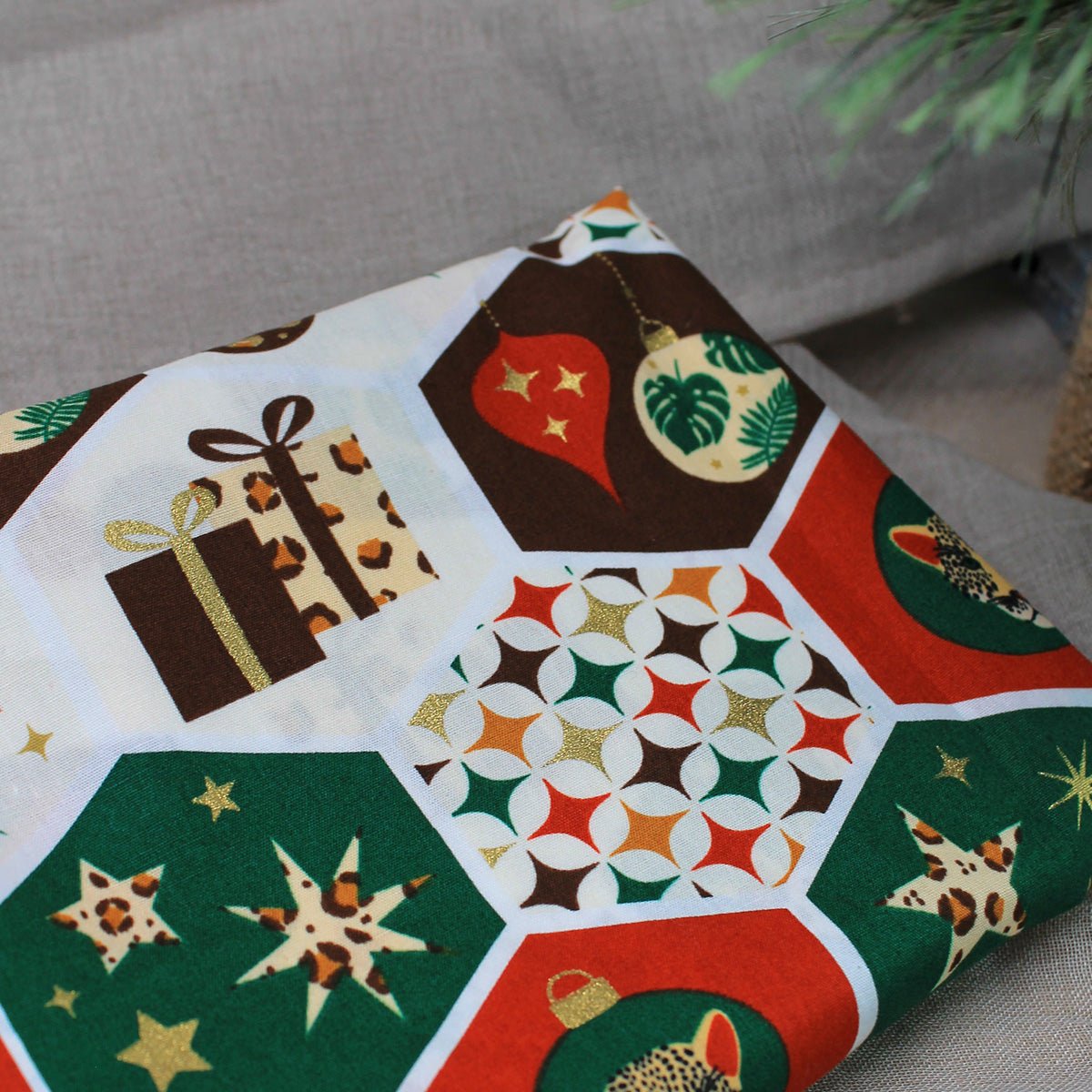 Nahaufnahme des bunten Weihnachtsstoffs mit verschiedenen festlichen Motiven für die handgemachten Anhänger.
