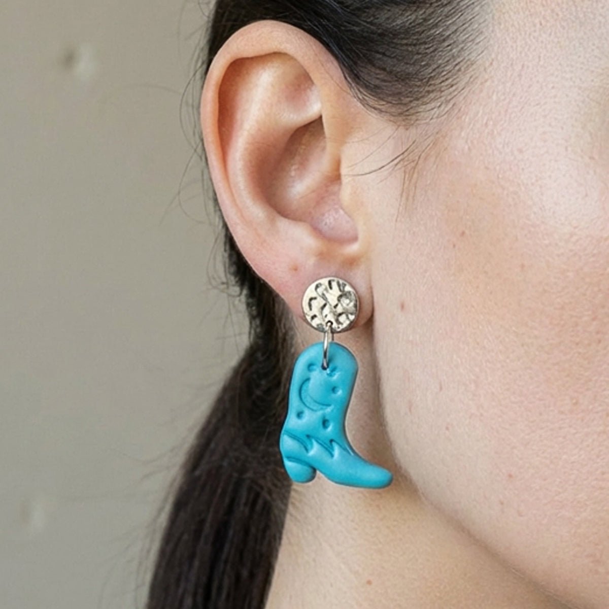 Frau trägt türkise Western Ohrringe in Form von Cowboy-Boots